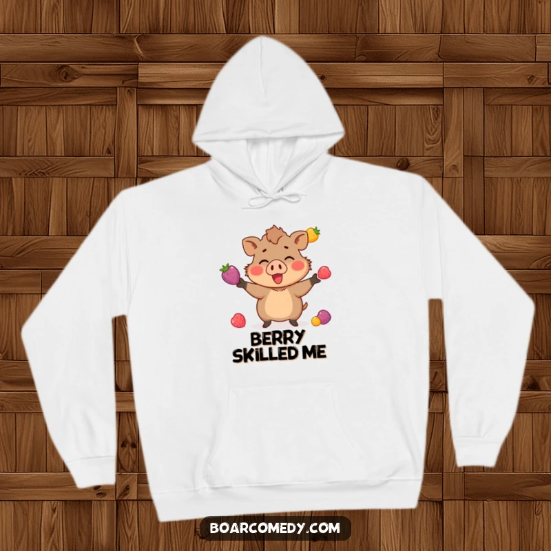 Funny hoodie showing a small boar character enthusiastically juggling three brightly colored berries, a charming display of skillful fun.